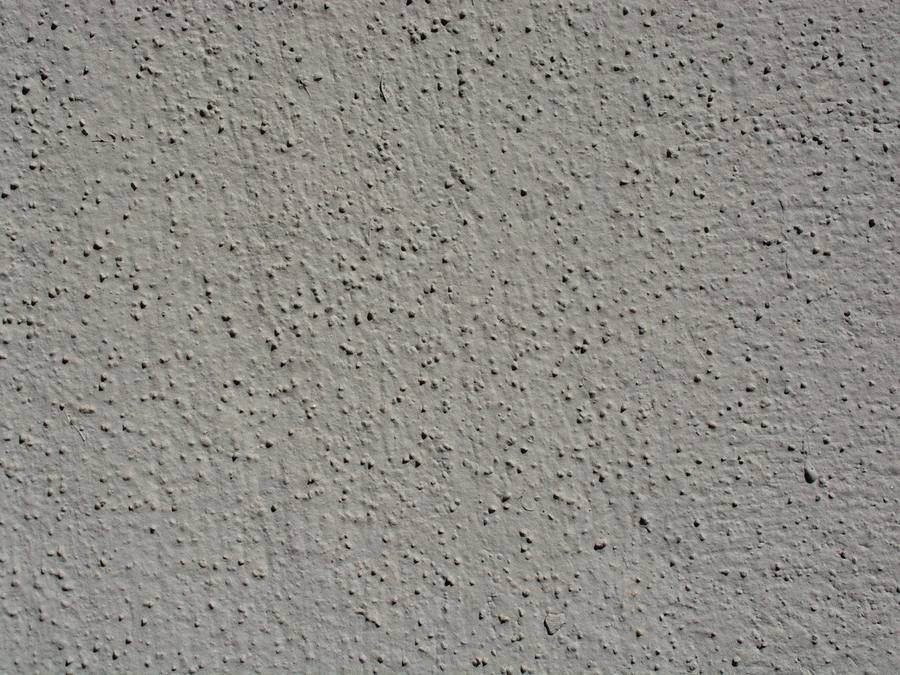 Detail of a textured dry-dash render finish showing the aggregate surface