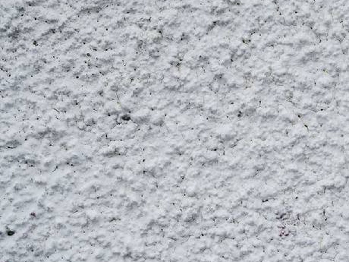 Close-up of a coarse white textured render, where texture gives dirt and moisture more places to settle
